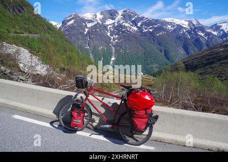Packed bike on a road in front of snow-covered mountains, a perfect adventure picture in Norwegian nature, Gaularfjell, pass road, Norway Stock Photo