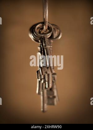 old keys hanging from the front on sepia background Stock Photo