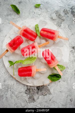 Homemade watermelon popsicles with ice against white marble background. Summer treat Stock Photo