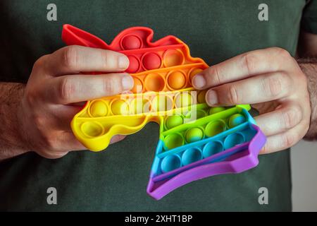 Hands holding rainbow push pop bubble sensory anti-stress squeeze toy with unicorn shape Stock Photo