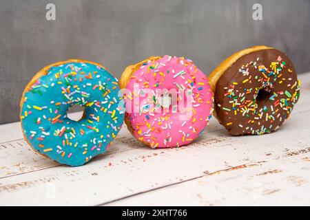 Delicious dessert. Pink, blue and chocolate donuts with multicolored sprinkles. Stock Photo
