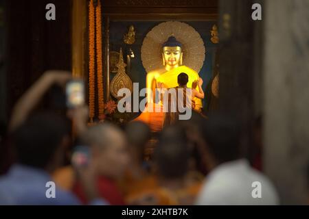 An on-duty monk covering the holy Golden Buddha statue with a new robe inside the chamber shrine of Mahabodhi Temple in Bodh Gaya, Bihar, India. Stock Photo