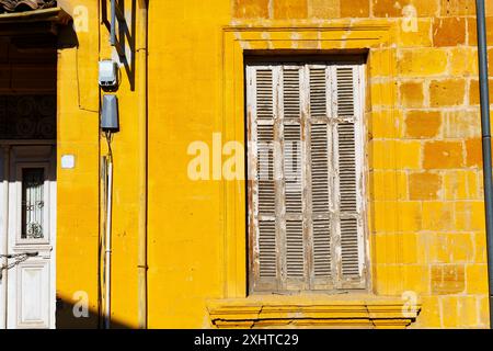 Yellow wall building with a window that is closed. Old house has a rustic appearance Stock Photo