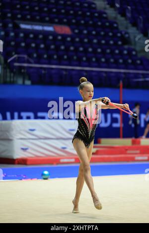 Young Female Rhythmic Gymnast Performing Routine with Ribbon on Competition Floor Stock Photo