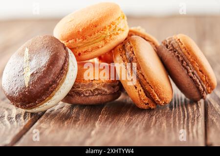 Multi-colored macaroons of coffee flavors on a wooden background are stacked in a slide. Stock Photo