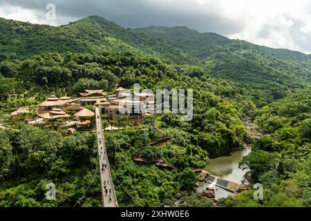 A long suspended wooden bridge in the forest park YaNoDa, A national park in the center of Hainan Island, China. Stock Photo