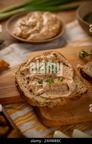 Slice of bread with greaves spread on wooden board, close up Stock Photo