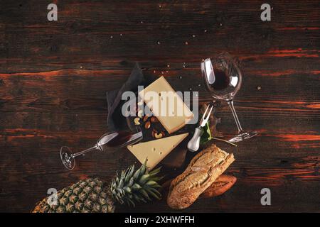 Gourmet cheese board accompanied by wine and fruits on rustic wooden table Stock Photo