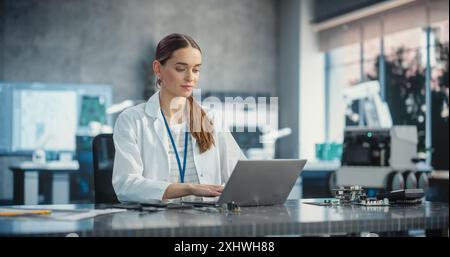 Portrait of Caucasian Young Female Scientist Using Laptop Computer, Working On Inventions in a Laboratory. Confident Professional Woman Working as Lead Engineer, Monitoring Technology Projects Stock Photo