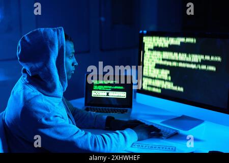 Code, man or hacker on technology screen for cybercrime, malware or phishing for stealing online data. Programmer, dark or typing software update on Stock Photo