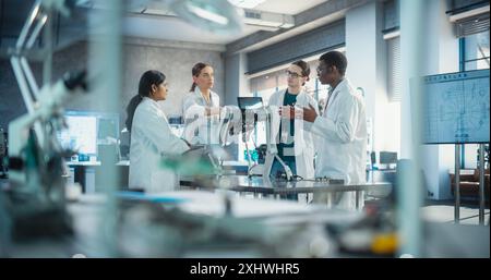 Professional Young International Team of Female and Male Engineers Discussing Industrial AI Robot Dog in Factory Development Workshop. Tech Facility with Machines, Computers and Research Equipment Stock Photo