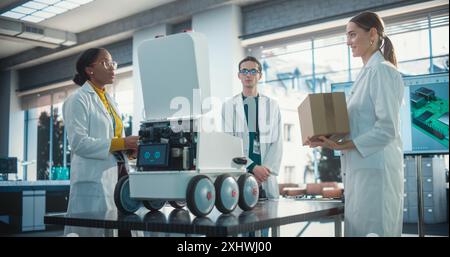 Diverse Team of Industrial Specialists Working on Remotely Controlled Robot, Using a Laptop. Young Male and Female Engineers Discussing Autonomous AI Delivery Assistant Prototype, Brainstorming Stock Photo