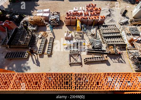 New wall made of ceramic blocks high above arranged improvised warehouse at open on the construction site,  pile of red blocks packed in plastic foil, Stock Photo