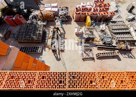 New wall made of ceramic blocks high above arranged improvised warehouse at open on the construction site,  pile of red blocks packed in plastic foil, Stock Photo