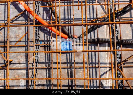 Protective ribbed plastic hoses for cables are placed and connected to distribution box, under rusty rebar, prepared for pouring concrete over them. R Stock Photo