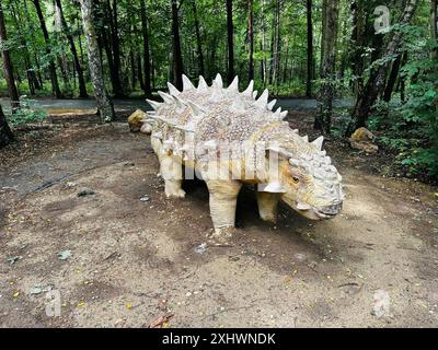 Realistic figure of an Sajchania dinosaur inforest park in Kazimierz Sosnowiec. Prehistoric predator create a fascinating element of the landscape, at Stock Photo