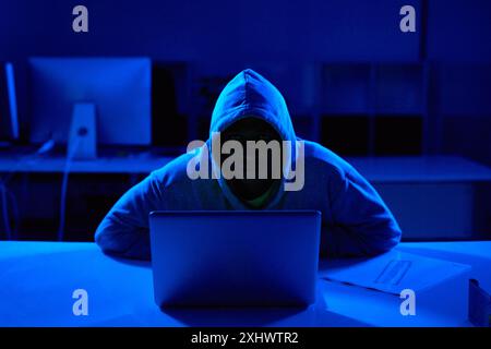 Person, hoodie or hacker with laptop for cybersecurity problem, malware or phishing for crime. Programmer, night and software update on technology Stock Photo