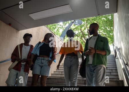 Interested black four girls and guys students down to stairs to underpass chatting going in college. Stock Photo
