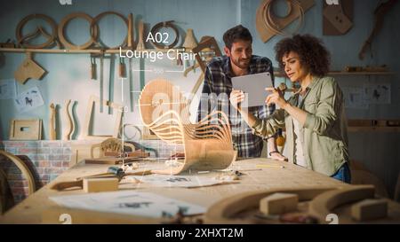 Multiethnic Female Furniture Designer is Showing Professional Male Carpenter New Chair Design On Tablet Computer. VFX 3D Hologram Edit Appears on the Work Table With Measurements for Production. Stock Photo