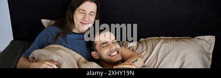 A young gay couple shares a tender moment, laughing and enjoying each others company in their bedroom. Stock Photo