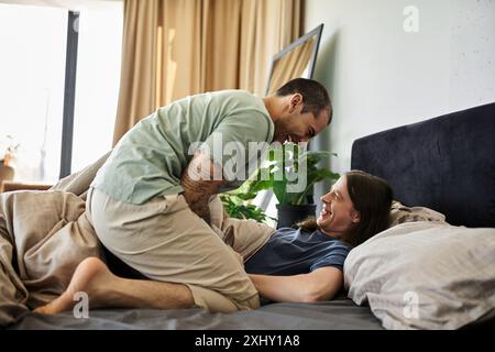 A young gay couple shares a loving moment in their bedroom, laughing together in the morning. Stock Photo