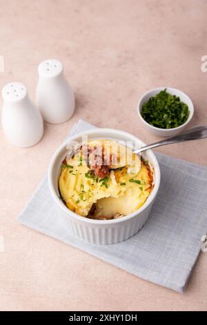 Shepherd's pie in a portioned white baking dish. Homemade traditional casserole (gratin) with minced meat and mashed potatoes. Selective focus, close- Stock Photo