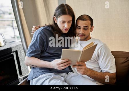 A young gay couple enjoys a quiet moment together in their modern home, reading a book. Stock Photo