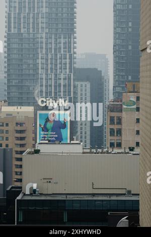 Cityscape view featuring a Citytv billboard with a diverse woman smiling, surrounded by tall buildings in an urban setting. Stock Photo