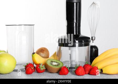 Hand blender kit, fresh fruits and strawberries on gray table against white background Stock Photo