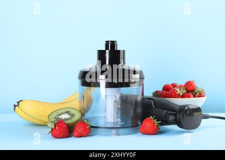 Hand blender kit, fresh fruits and strawberries on light blue background Stock Photo