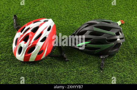 Two protective helmets on green grass. Sports equipment Stock Photo