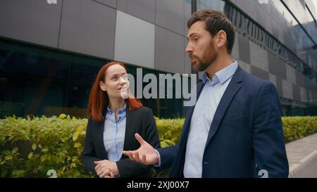 Two people partners co-workers business colleagues walking in city talking discuss corporate deal talk walk together collaboration teamwork outdoors Stock Photo