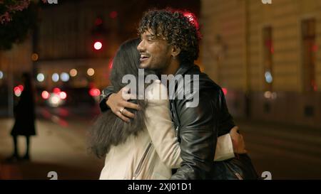 Indian Arabian couple love guy girl woman man friends boyfriend girlfriend meeting in dark night urban evening city dating hugging greeting male show Stock Photo