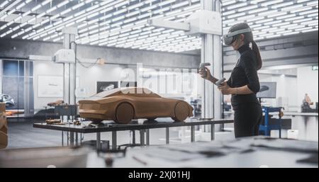 Female Car Designer Wearing a Virtual Reality Headset and Using Controllers to Work on a Concept Car Made Out of Plasticine Modeling Clay. Talented Designer Working in VR Set to Analyze the Vehicle Stock Photo