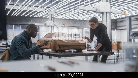 Young Female Apprentice Car Modeler Working with Black Senior Automotive Designer on Creating a 3D Polymer Clay Model of a Modern Electric Car. Team of Diverse Specialists Working in Creative Agency Stock Photo