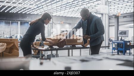 Young Apprentice Car Modeler Advising with Senior Automotive Designer on Creating a 3D Polymer Clay Model of a Modern Electric Car. Team of Diverse Specialists Working in Creative Agency Stock Photo