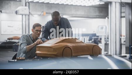 Enthusiastic Teamwork of Two Diverse Creative Colleagues Working in an Automotive Development Design Agency. Professional Sculptor Working Together with an Engineer, Discussing the Prototype Vehicle Stock Photo