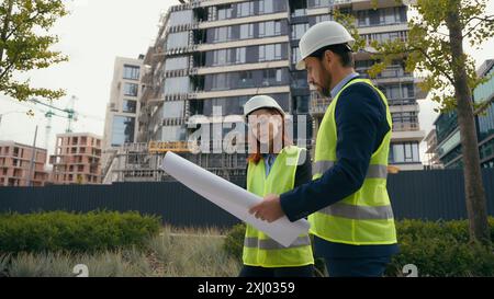 Two architects urban build workers Caucasian colleagues partners in safety hat and reflective vest talking discuss city blueprint builders engineers Stock Photo