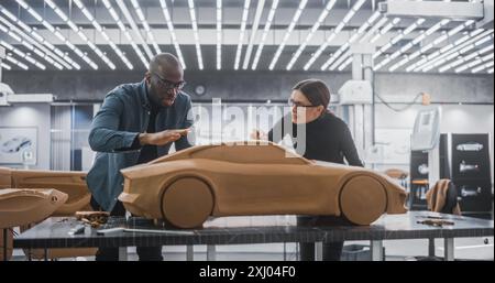Enthusiastic Teamwork of Two Diverse Creative Colleagues Working in an Automotive Development Design Agency. Professional Sculptor Working Together with an Engineer, Discussing Prototype Vehicle Stock Photo