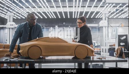 Enthusiastic Teamwork of Two Diverse Creative Colleagues Working in Automotive Development Design Agency. Professional Sculptor Working Together with an Engineer, Discussing Prototype Vehicle Stock Photo