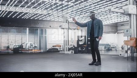 Black Male Car Designer Wearing a Virtual Reality Headset and Using Controllers to Work on a Concept Car Or Aerodynamics. Talented Design Professional Working in VR Set to Analyze And Test the Vehicle Stock Photo
