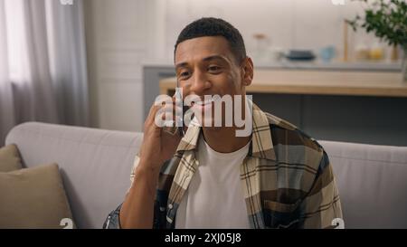 Smiling African American ethnic man carefree guy smile male talking call smartphone talk speaking mobile phone speak communicate laughing conversation Stock Photo