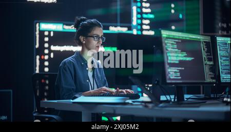 Female Programmer Working in Monitoring Control Room, Surrounded by Big Screens Displaying Lines of Programming Language Code. Portrait of Woman Creating Software. Abstract Futuristic Coding Concept Stock Photo