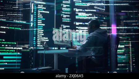 Black Male Developer Thinking and Typing on Computer, Surrounded by Big Screens Showing Coding Language. Professional Programmer Creating Software, Running Coding Tests. Abstract Programming Concept Stock Photo