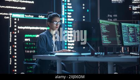 Female Programmer Working in Monitoring Control Room, Surrounded by Big Screens Displaying Lines of Programming Language Code. Portrait of Woman Creating a Software. Futuristic Coding Concept. Stock Photo