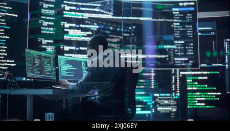 Shot of a Man Working as a Developer, Surrounded by Big Screens Displaying Lines of Code in a Monitoring Room. Black Male Programmer Using Desktop Computer, Analysing Data, Creating AI Software Stock Photo