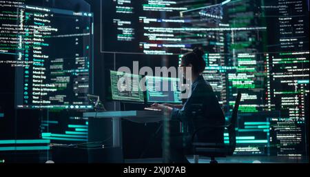 Professional Female Programmer Working in a Monitoring Control Room, Surrounded by Big Screens Displaying Lines of Programming Language Code. Portrait of Woman Creating a Software and Coding Stock Photo