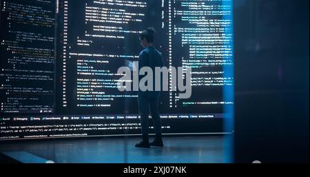 Portrait of Young Woman Working on Laptop Computer, Looking at Big Digital Screen Displaying Back-end Code Lines. Professional Programmer Developing a Big Data Interface Software Project Concept. Stock Photo