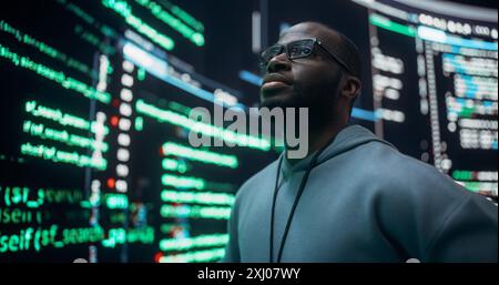 Portrait of Worried Professional Programmer Fixing a Bug, Dealing with Crashing System. Young Black Man Looking at Big Digital Screens Glitching While Displaying Code Lines, Thinking of Solutions Stock Photo