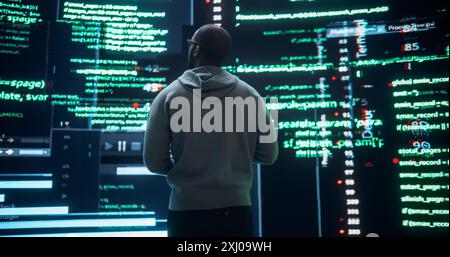 Back View of Young Black Man Looking Towards a Big Digital Screens Glitching While Displaying Code Lines. Worried Professional Programmer Fixing a Software Bug, Dealing with Crashing System Stock Photo